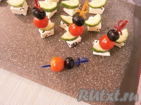 На шпажки нанизать по одной оливке и по одному помидорчику черри (помидоры нужно брать самые маленькие). И этими шпажками закрепить огурцы на сыре. 