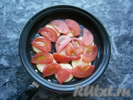 Затем кабачки перевернуть, огонь сделать минимальным. Поверх кабачков выложить в один слой нарезанные кружками (или полукружками) помидоры. 