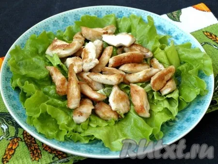 Салатные листья порвать руками и выложить на тарелку. Сверху разложить кусочки курицы. 