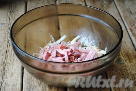 Колбасу освободить от оболочки, нарезать соломкой и выложить к капусте. 