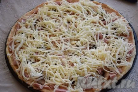 Покрываем начинку пиццы сыром, натертым на крупной терке. 