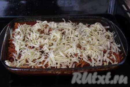 Поставить форму со спагетти в томатном соусе в разогретую духовку и готовить минут 25 при температуре 180 градусов. Затем достать форму, присыпать спагетти натёртым сыром и поставить обратно в духовку на минут 7-10 (до расплавления сыра).