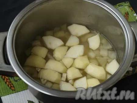 Яблоко очистить от кожуры, удалить сердцевину и произвольно нарезать. Также нарезать очищенный чеснок. Когда картошка сварится, добавить в суп яблоки и чеснок, варить 5 минут. 