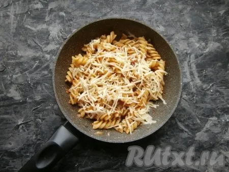 Прогреть макароны с помидорами на сковороде на умеренном огне 3-4 минуты, затем посыпать их натёртым на крупной тёрке сыром (немного сыра оставить для подачи). Убрать сковороду с огня, накрыть крышкой и оставить доходить минуты на 3-4. 