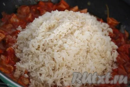 Добавить распаренный рис в сковороду к мясу и тщательно перемешать.