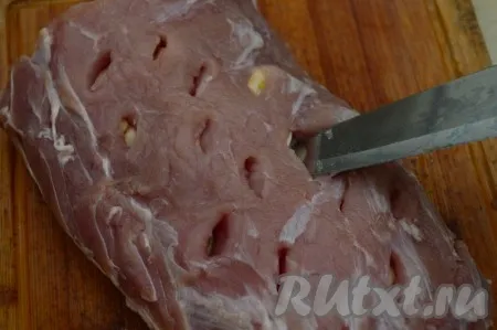 Свежую (или размороженную) свинину нашпиговать со всех сторон чесноком, для этого сделать по всей поверхности свинины острым ножом надрезы, в которые вставить пластины чеснока.