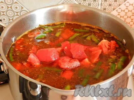 Выложить рис в кастрюлю с мясом и овощами, сверху положить помидоры. Довести до кипения. 