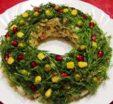 На фото украшенный укропом, зернами граната и кукурузой салат Рождественский венок