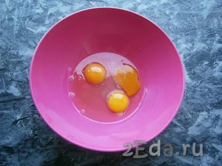 Для приготовления яичного коржа разбить в миску яйца, всыпать щепотку соли.
