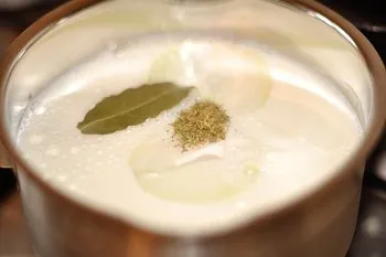 Молоко нагревается с луком лавровым листом и тимьяном