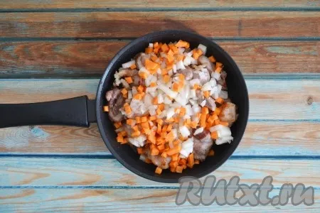Лук и морковь очистить, нарезать мелкими кубиками и выложить в сковороду поверх мяса. 