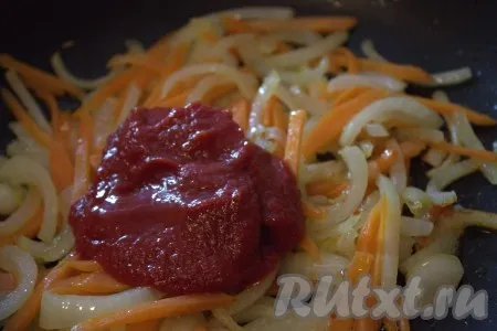 К обжаренным овощам добавить томатную пасту, тщательно перемешать и обжарить 1 минуту. 