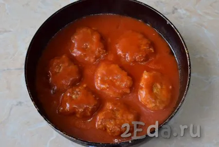 После закипания накройте сковороду крышкой, сделайте огонь минимальным и тушите куриные тефтели в томатном соусе минут 15.