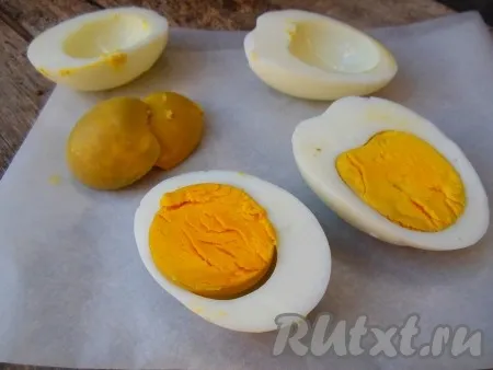 Отварные куриные яйца очистите, разрежьте на две части. Отделите желтки от белков. Белки измельчите при помощи толкушки для картофеля или ножом. 