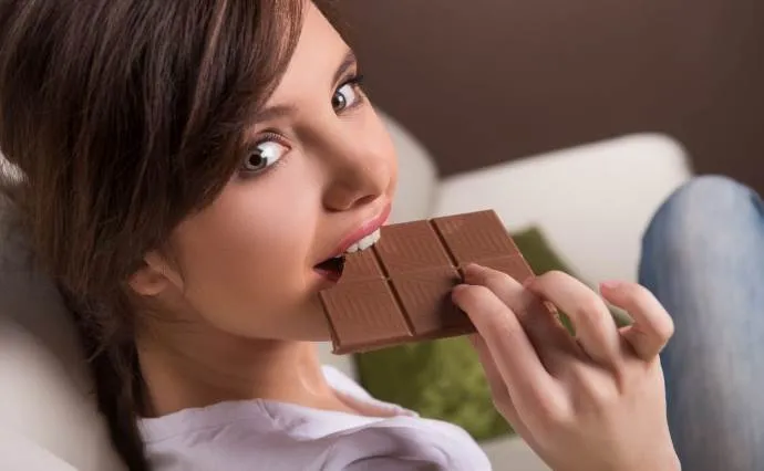 Девушка кусает шоколадку