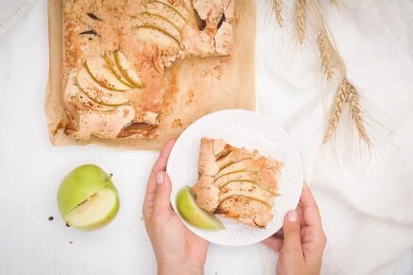 top view on womans hands holding plate with homemade crispy apple pie - Постная шарлотка