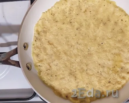 На смазанной растительным маслом разогретой сковороде лопаткой или руками равномерно распределить картофельное тесто. На сковороде с диаметром дна 20 см получится основа для картофельной пиццы толщиной 0,5 см. Выпекать картофельную основу под закрытой крышкой на среднем огне 8 минут.