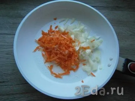 В ту же сковороду влить оставшееся растительное масло, выложить 0,5 луковицы, нарезанной кусочками, и натертую на крупной терке морковь.