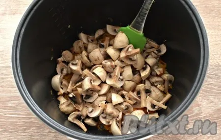 Шампиньоны нарезаем четвертинками. Перекладываем грибы в чашу к овощам и обжариваем, иногда перемешивая, минут 5.