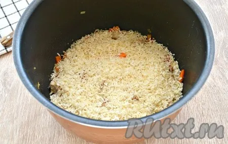 Рис промыть, слить воду. Выложить промытый рис ровным слоем поверх свинины и овощей. 