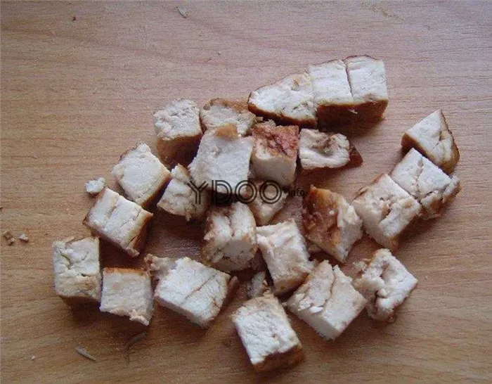 запеченная куриная грудка, нарезанная кубиками, лежит на деревянной доске