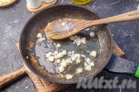 В эту же сковороду, где жарилась курица, добавьте очищенный и нарезанный на тонкие пластины чеснок. Обжаривайте его 1 минуту, помешивая. 