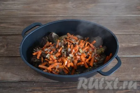 Лук и морковь выложить на сковороду, в которой обжаривали кусочки гуся. Обжаривать овощи 3-4 минуты, периодически помешивая, затем переложить в казан с мясом, вылить образовавшуюся жидкость со сковороды. Добавить 2 стакана кипятка, накрыть крышкой и поставить на огонь. 