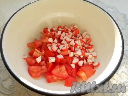 К нарезанным крабовым палочкам добавить помидоры, нарезанные небольшими кубиками. 