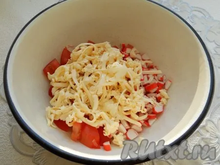 Сыр натереть на крупной терке, чеснок пропустить через пресс, добавить в салат к помидорам и крабовым палочкам. 
