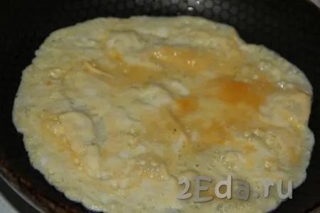 Влить в сковороду немного растительного масла, разогреть, затем вылить взбитое яйцо. Равномерно распределить яичную массу по поверхности сковороды, жарить блинчик на среднем огне.