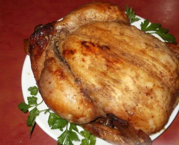 Запечённая целиком курица с мёдом и горчицей на большой белой тарелке