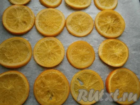 Кружочки апельсинов вынуть из сиропа и разложить их на противне, застеленном пергаментом. Сироп можете в дальнейшем использовать для пропитки бисквитов или для приготовления других десертов. 