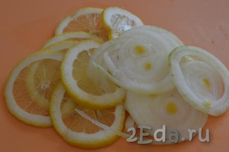Оставшуюся часть лимона нарезать на тонкие кружочки. Репчатый лук очистить, промыть и нарезать на тонкие кольца.