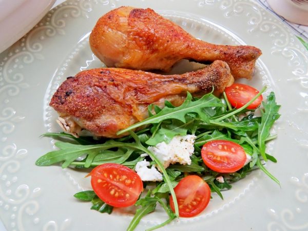 Куриные голени с румяной корочкой на тарелке с салатом из рукколы, черри и сыра