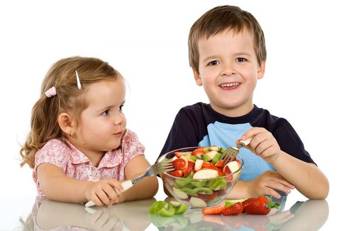 Мальчик и девочка едят фруктовый салат