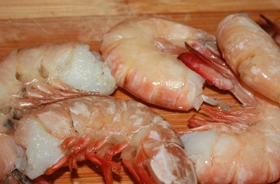 Сложите замороженные очищенные морепродукты в дуршлаг