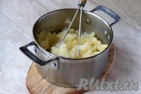 С готового картофеля слить воду и переложить в другую кастрюлю, чтобы не повредить чашу мультиварки. Размять горячий картофель толкушкой. 
