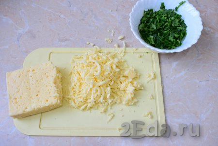 Пока омлет готовится, натрите сыр на крупной тёрке и мелко нарежьте зелень.
