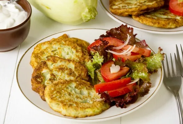 zucchini fritters with tomato salad on a white table - Постные оладьи из кабачков